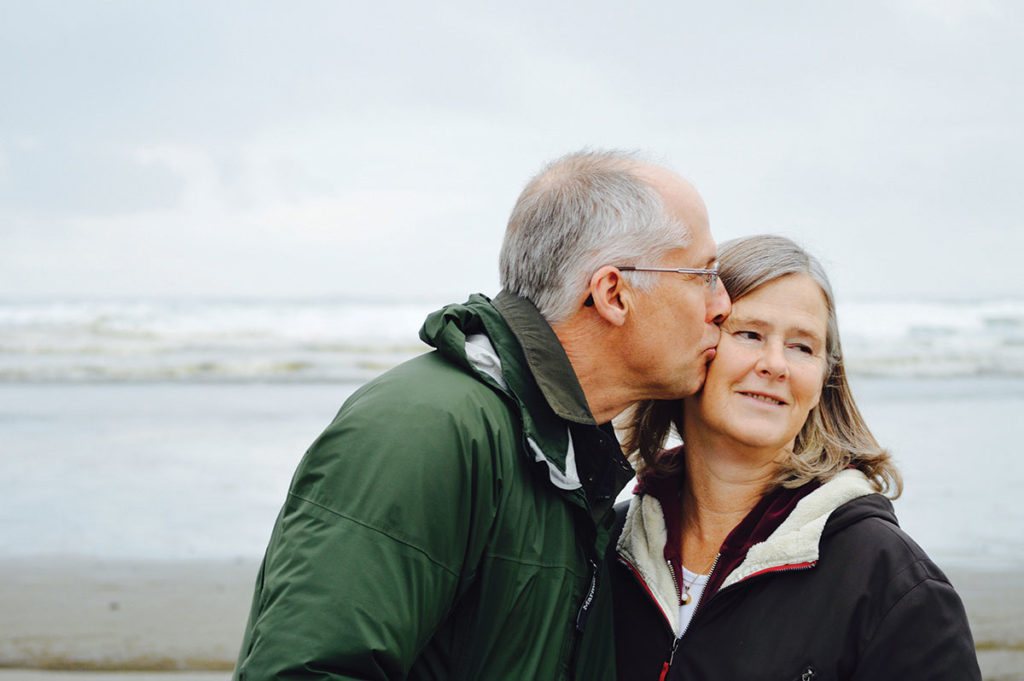 Older couple kissing on the beach as they consider their vascular health. 